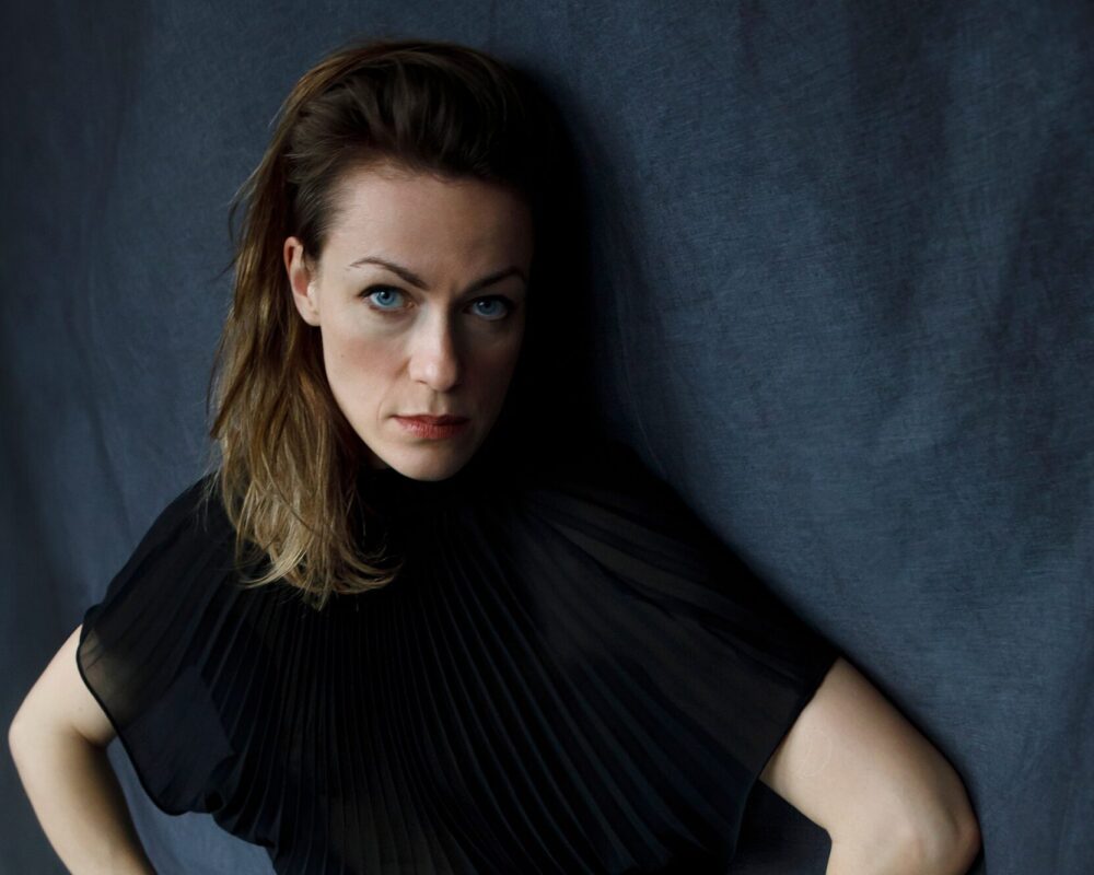 Musikerin Charlotte Brandi vor blauem Tuch in schwarzem Shirt