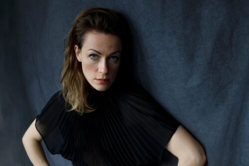 Musikerin Charlotte Brandi vor blauem Tuch in schwarzem Shirt